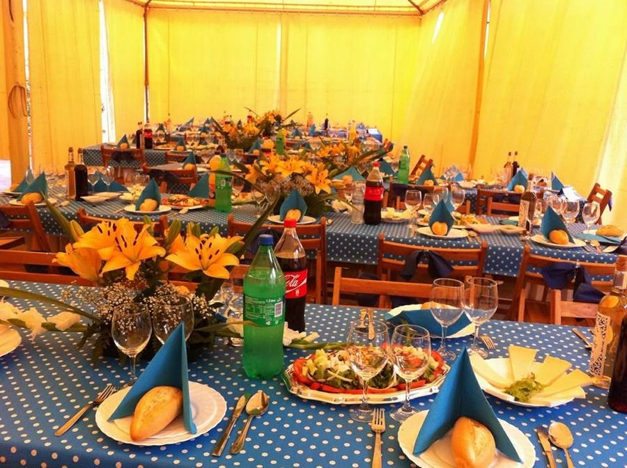 Event tent with blue polka-dot tablecloths and yellow lilies, set for a celebration